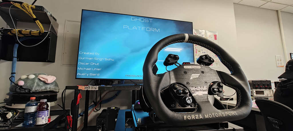 Driving simulator set up with a steering wheel in the foreground with a large TV monitor in the background. 